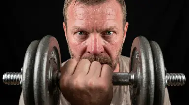 man lifting heavy dumbbell close-up