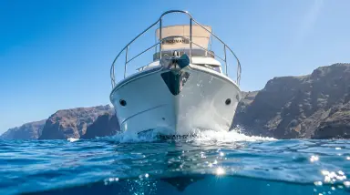 white yacht on blue sea with rocky cliffs