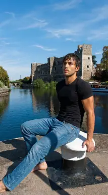 man sitting by river with castle backdrop