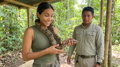 woman holding boa constrictor in jungle