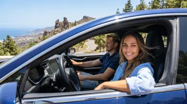couple enjoying scenic coastal drive in blue car