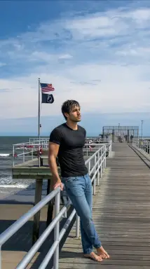 Man Leaning on Boardwalk Pier with Flags