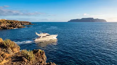 yacht cruising coastal waters with cliffs and island